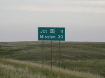 Highway sign east of Upper Cut Meat (Jct 63 11 miles, Mission 30 miles).